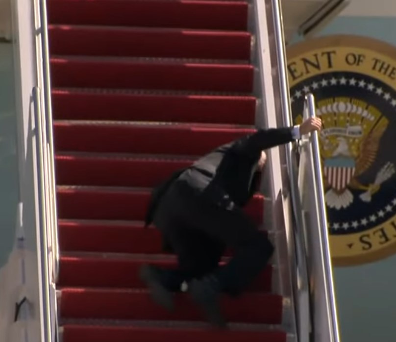 Бајден на колена, неколку пати паѓа додека се качува на претседателскиот авион